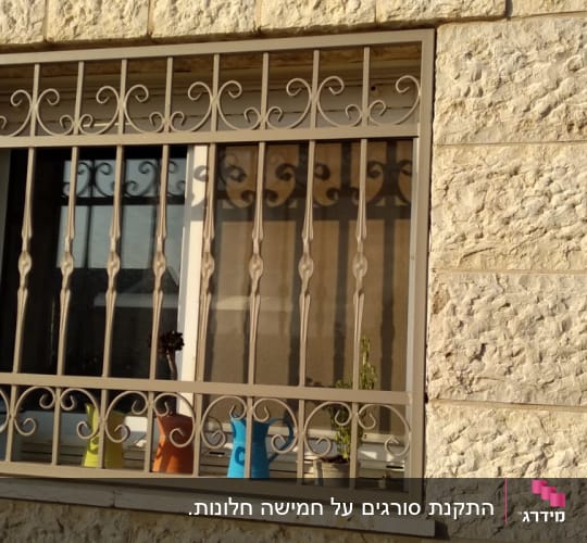 סורגי מתכת מעוצבים על חלון אבן